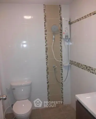 Modern bathroom with shower and toilet in sleek tiled design.