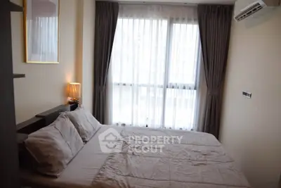 Cozy bedroom with soft lighting and large window with curtains in modern apartment.