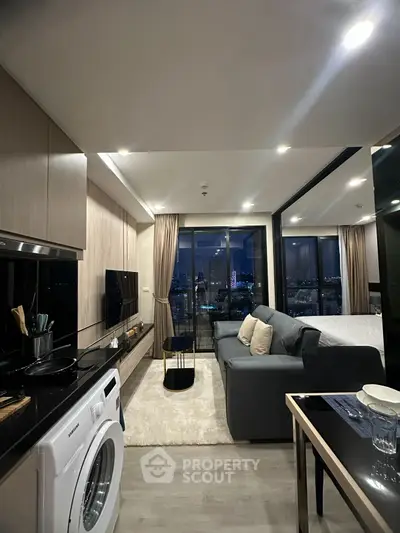 Modern living room with city view, featuring sleek design and integrated kitchen appliances.
