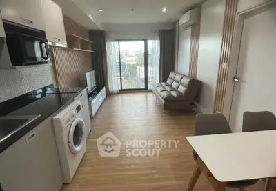 Modern open-layout living room with kitchen, featuring sleek appliances and a city view balcony.