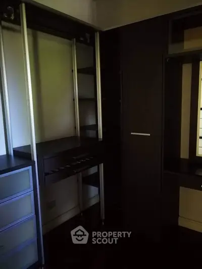 Spacious walk-in closet with dark wood finish and ample storage space.