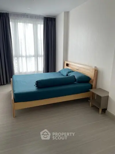 Modern bedroom with minimalist design and large window for natural light.