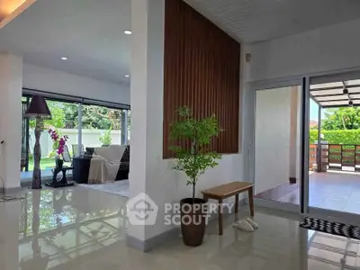 Spacious living room with modern decor and large windows opening to a lush garden view.