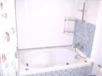 Modern bathroom with elegant bathtub and stylish blue tile accents.