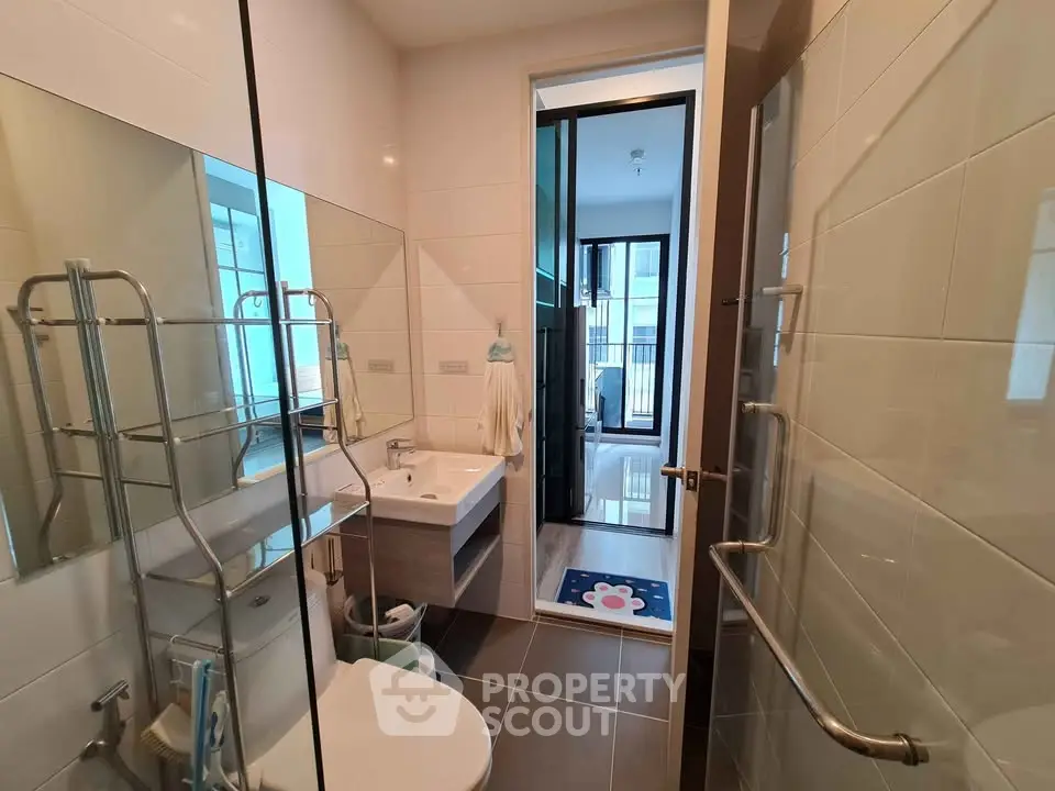 Modern bathroom with sleek fixtures and glass shower door in a contemporary apartment.