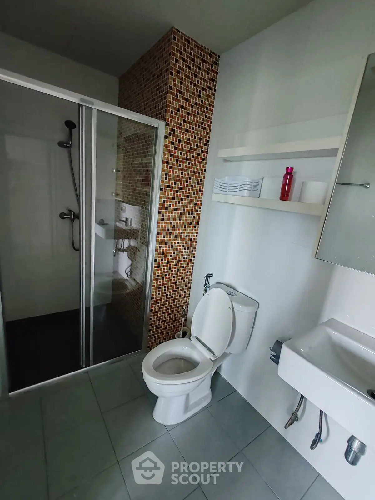 Modern bathroom with shower and toilet featuring mosaic tile accents.