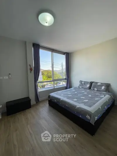 Spacious bedroom with large window and modern decor in a bright apartment.