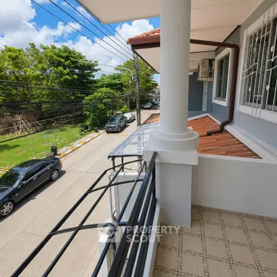 Charming balcony view from modern home overlooking a serene street and lush greenery.