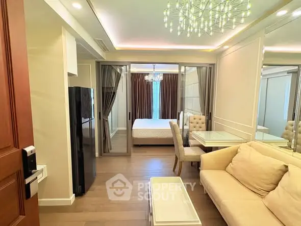 Modern apartment interior with open living room and bedroom, featuring elegant decor and lighting.