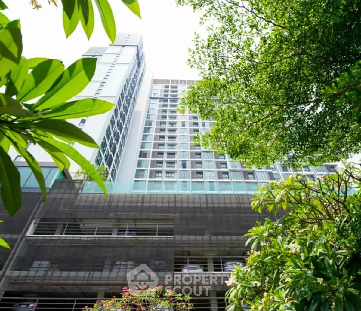 Modern high-rise building surrounded by lush greenery, offering urban living with a touch of nature.