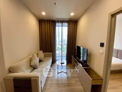 Modern living room with cozy sofa and TV, featuring a city view through large window.