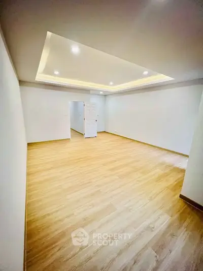 Spacious empty room with wooden flooring and modern ceiling lights