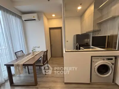 Modern apartment interior with open kitchen and dining area featuring washing machine and air conditioning.