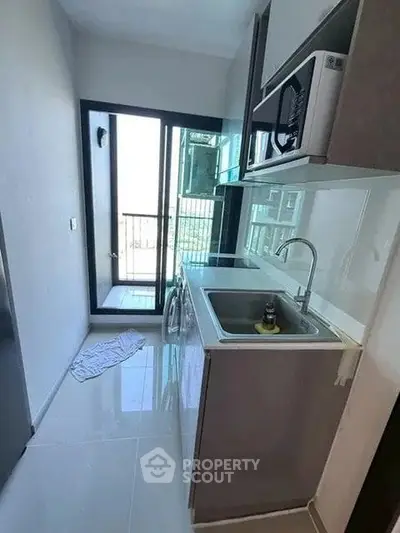 Compact kitchen with modern appliances and balcony access in urban apartment