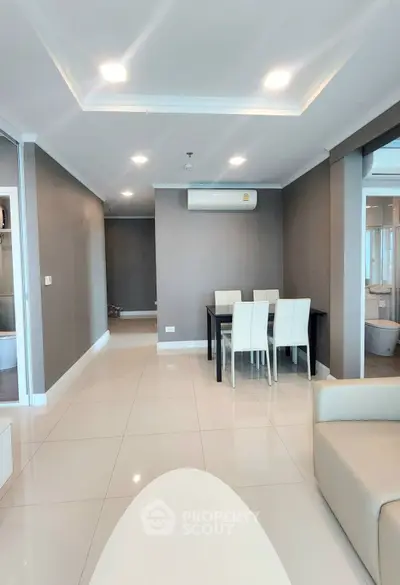 Modern living room with dining area, sleek furniture, and bright lighting in a contemporary apartment.