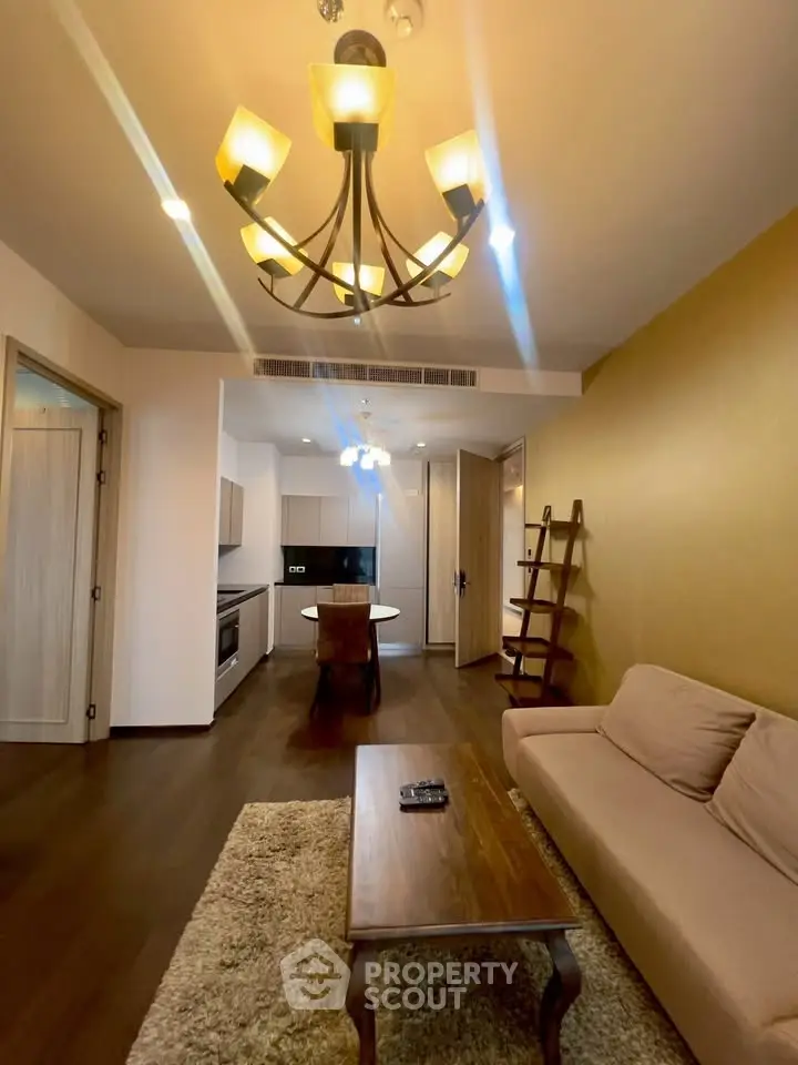 Modern living room with elegant chandelier and cozy seating area in open layout apartment.
