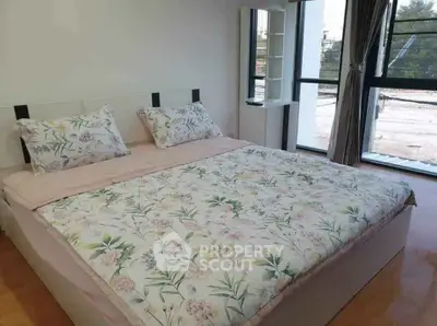 Spacious bedroom with large windows and floral bedding in modern apartment