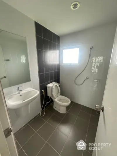 Modern bathroom with sleek design, featuring a shower, toilet, and sink with a large mirror.