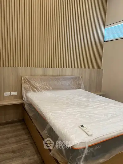 Modern bedroom with sleek wooden paneling and a new mattress, perfect for a cozy retreat.