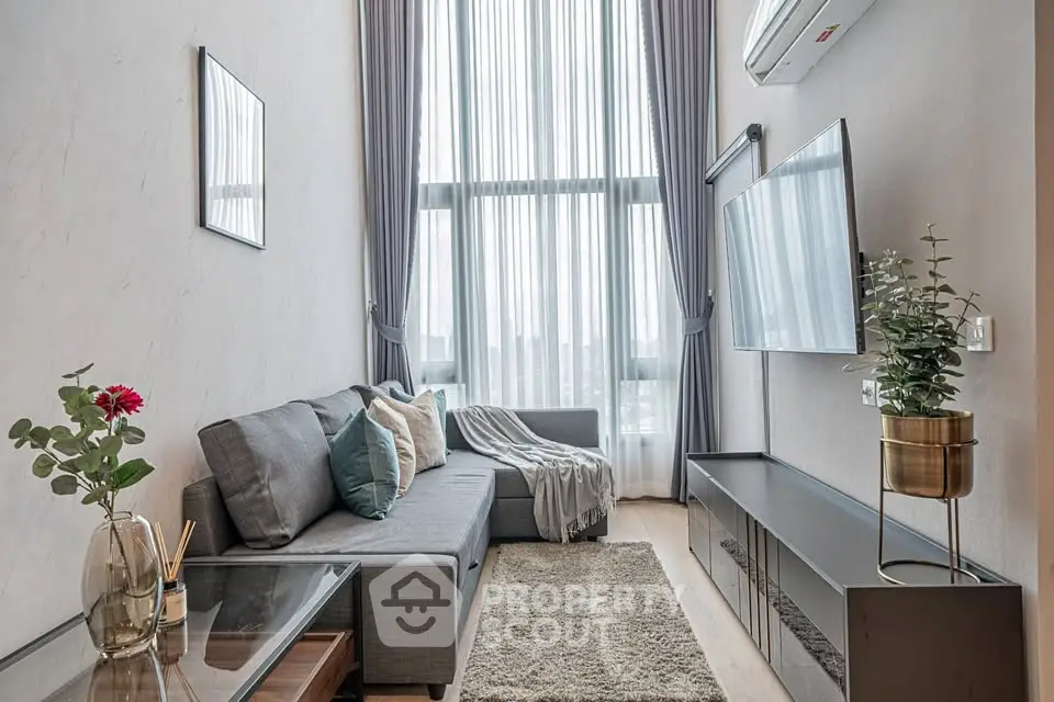 Modern living room with high ceilings, large windows, and stylish decor in a contemporary apartment.