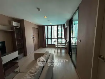 Modern living room with large windows and dining area in a stylish apartment.