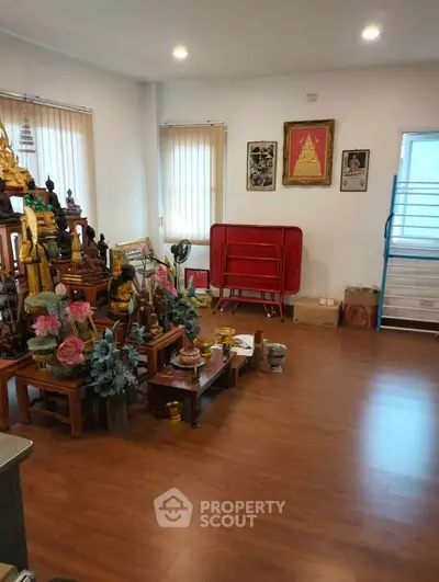 Spacious room with wooden flooring, adorned with decorative statues and art, ideal for a serene living space.