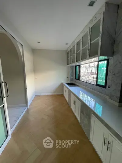 Modern kitchen with sleek cabinetry and large window for natural light.