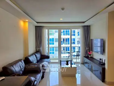 Modern living room with leather sofa, large windows, and city view in a high-rise apartment.