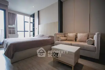 Modern bedroom with cozy sofa and large windows offering natural light