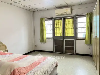 Cozy bedroom with natural light, featuring a comfortable bed and ample storage space.