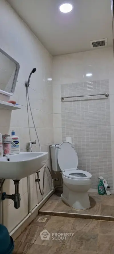 Modern bathroom with sleek fixtures and neutral tiles, featuring a shower and toilet.