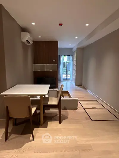Modern living room with sleek furniture and wooden flooring, featuring a cozy dining area and large windows.