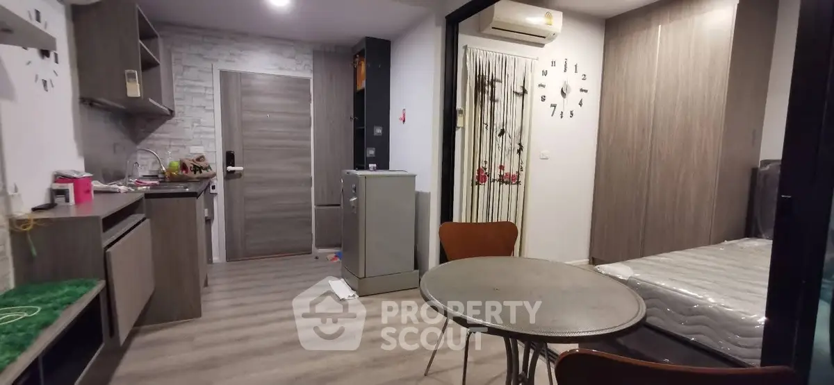 Modern studio apartment with open layout, featuring a compact kitchen and cozy living area.