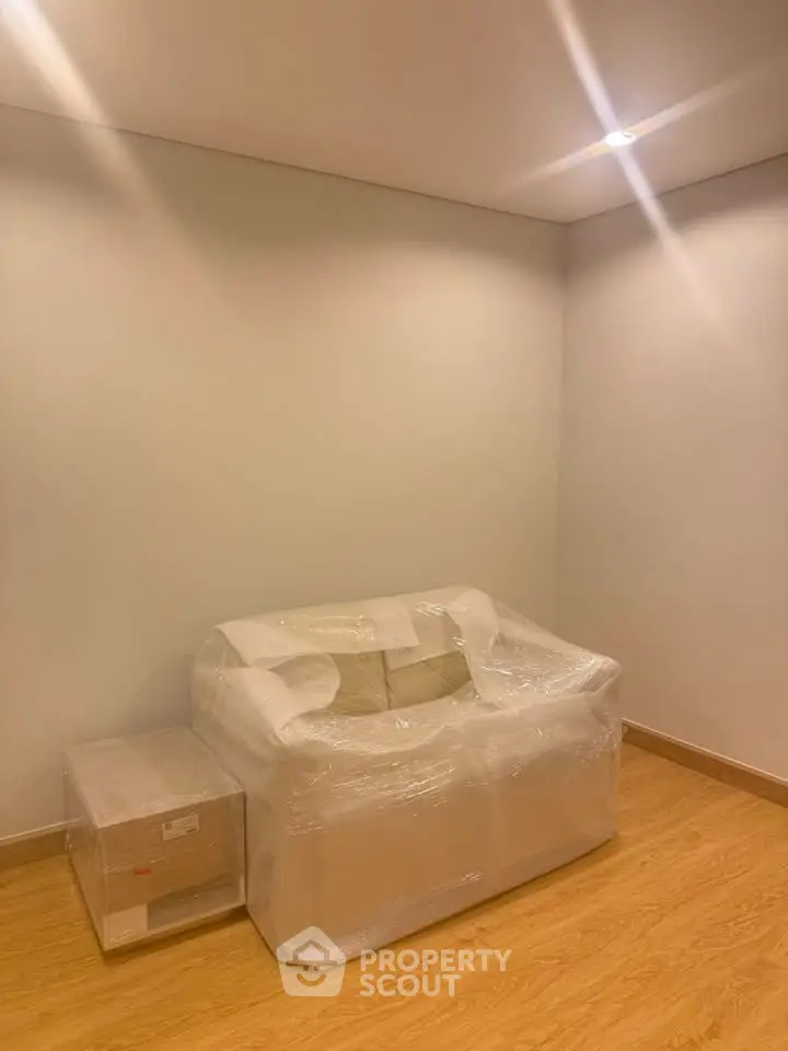 Minimalist living room with wrapped furniture and wooden flooring, perfect for modern interiors.