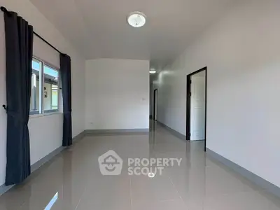 Spacious unfurnished room with glossy tiled floors and large window, ideal for customization.