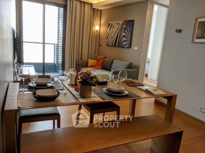 Modern dining area with elegant table setting in a stylish apartment, featuring a cozy living room and balcony view.