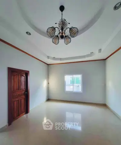 Spacious empty room with elegant chandelier and polished floor, perfect for customization.