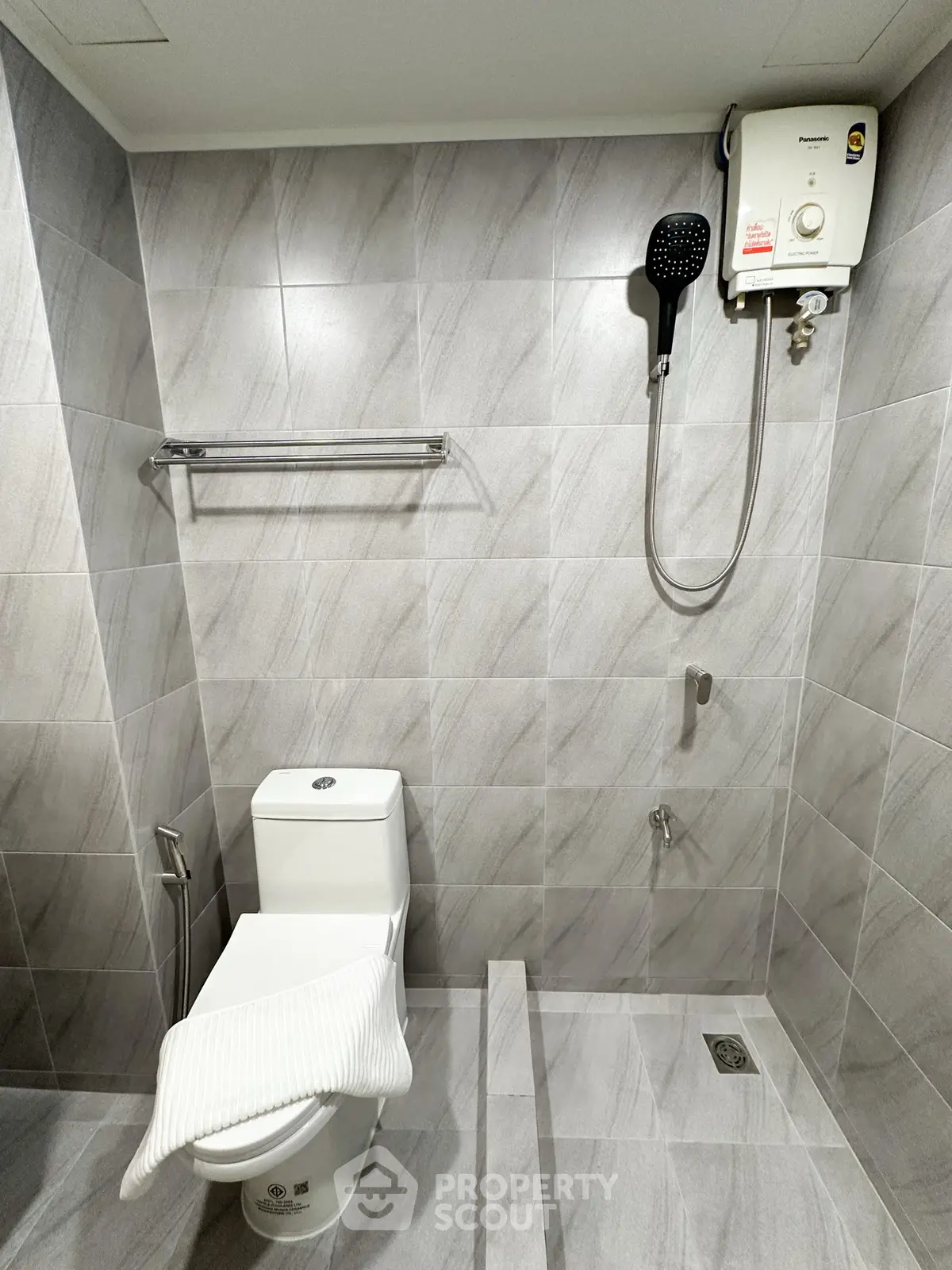 Modern bathroom with sleek tiles and water heater, ideal for contemporary living.