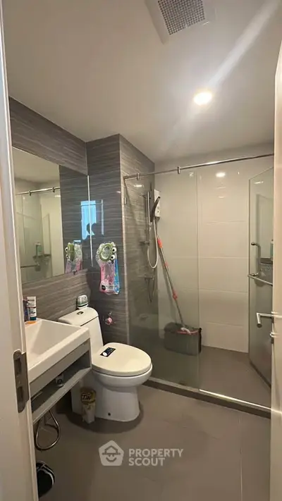 Modern bathroom with glass shower and sleek fixtures in contemporary apartment.