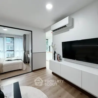 Modern living room with sleek TV unit and view into cozy bedroom