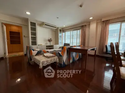 Spacious living room with hardwood floors and modern furniture in a well-lit apartment.