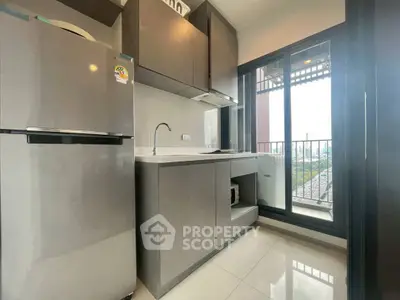 Modern kitchen with sleek cabinets and large window offering natural light and city view.