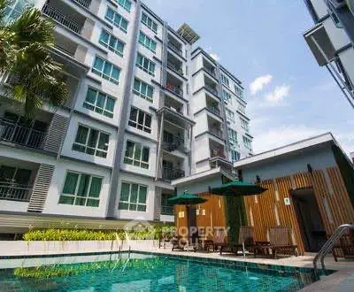 Modern apartment building with pool and sun loungers in a vibrant urban setting.