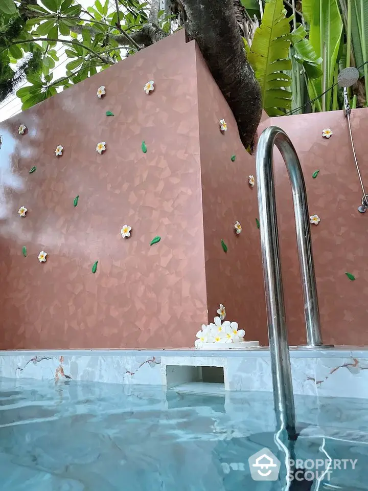 Luxurious outdoor pool with elegant floral wall design and lush greenery