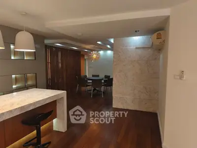 Modern open-plan living and dining area with stylish lighting and marble accents.