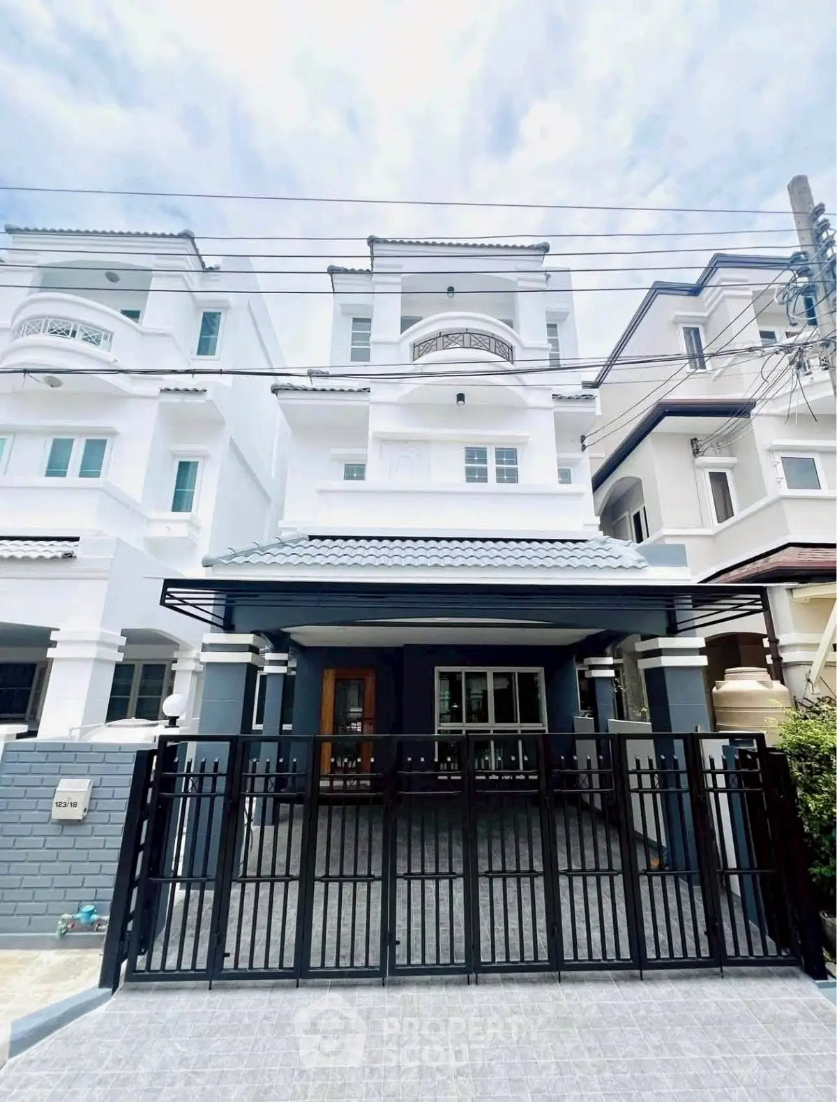 Elegant multi-story white townhouse with modern facade and gated entrance