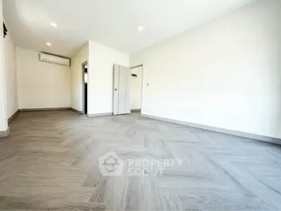 Spacious empty room with modern flooring and air conditioning, perfect for customization.