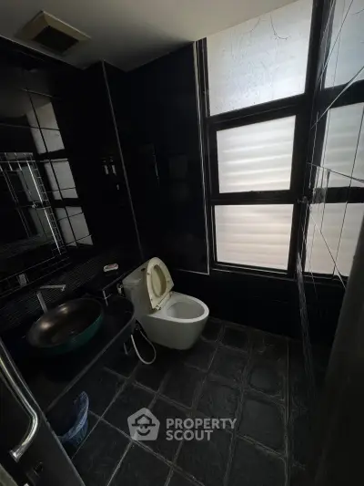 Modern bathroom with sleek black tiles and large window for natural light.