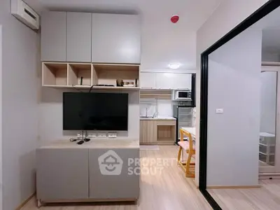 Modern apartment interior with open kitchen and living area, featuring sleek cabinetry and light wood flooring.