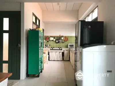 Charming kitchen with green cabinetry and modern appliances in cozy home.